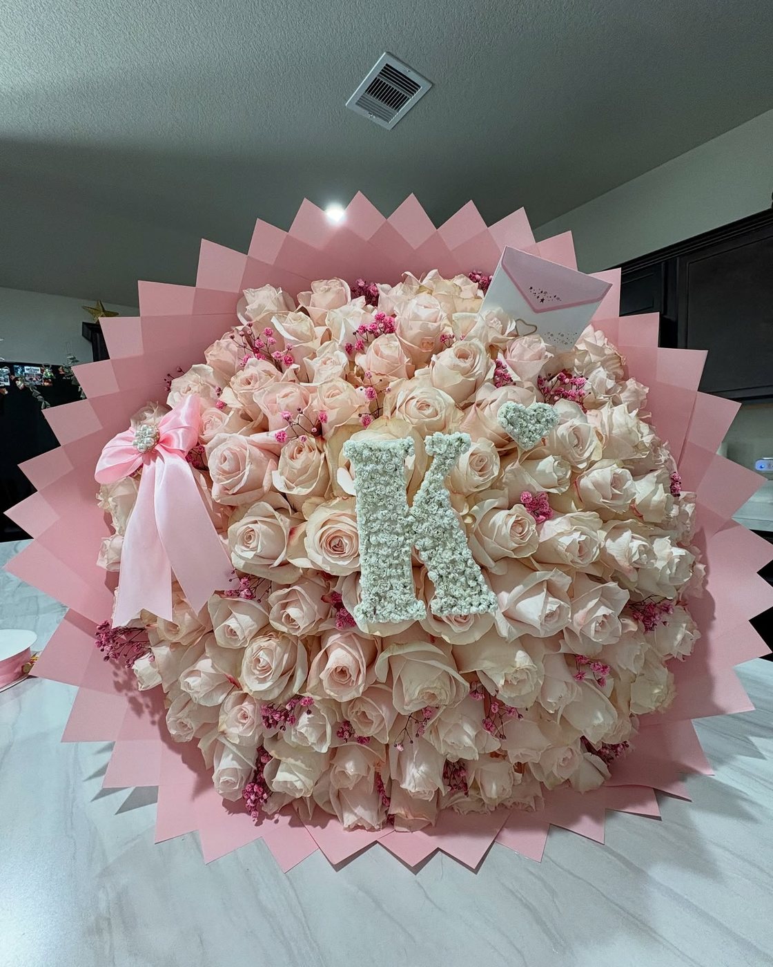 Fifty pale pink roses with a pearl initial K and a rhinestone tiara